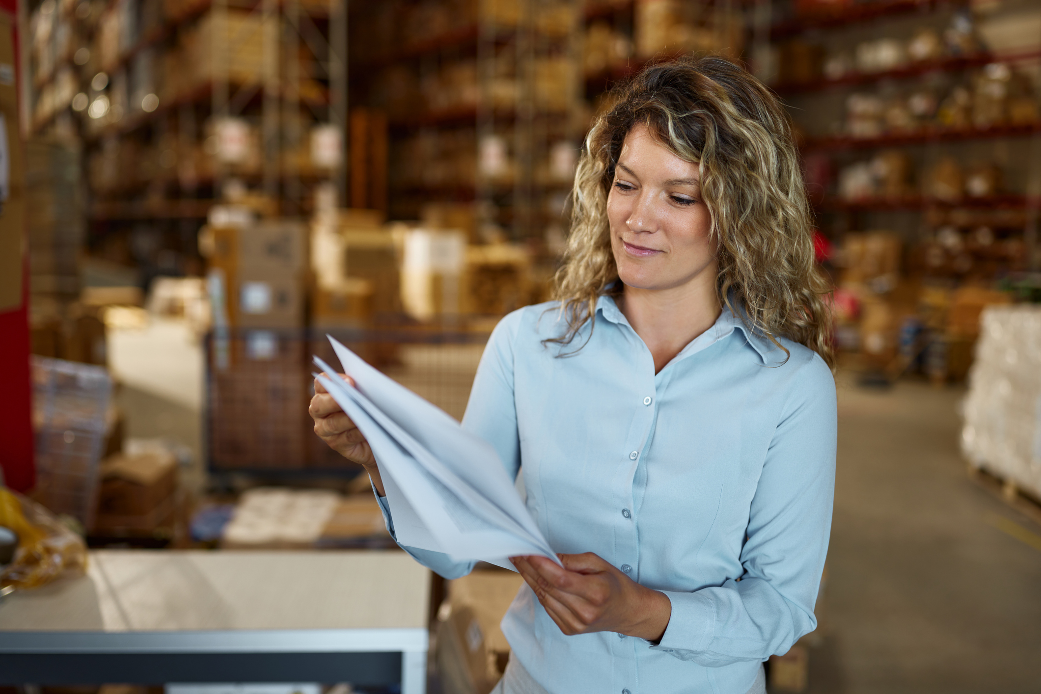 A woman checking through paperwork in a warehouse