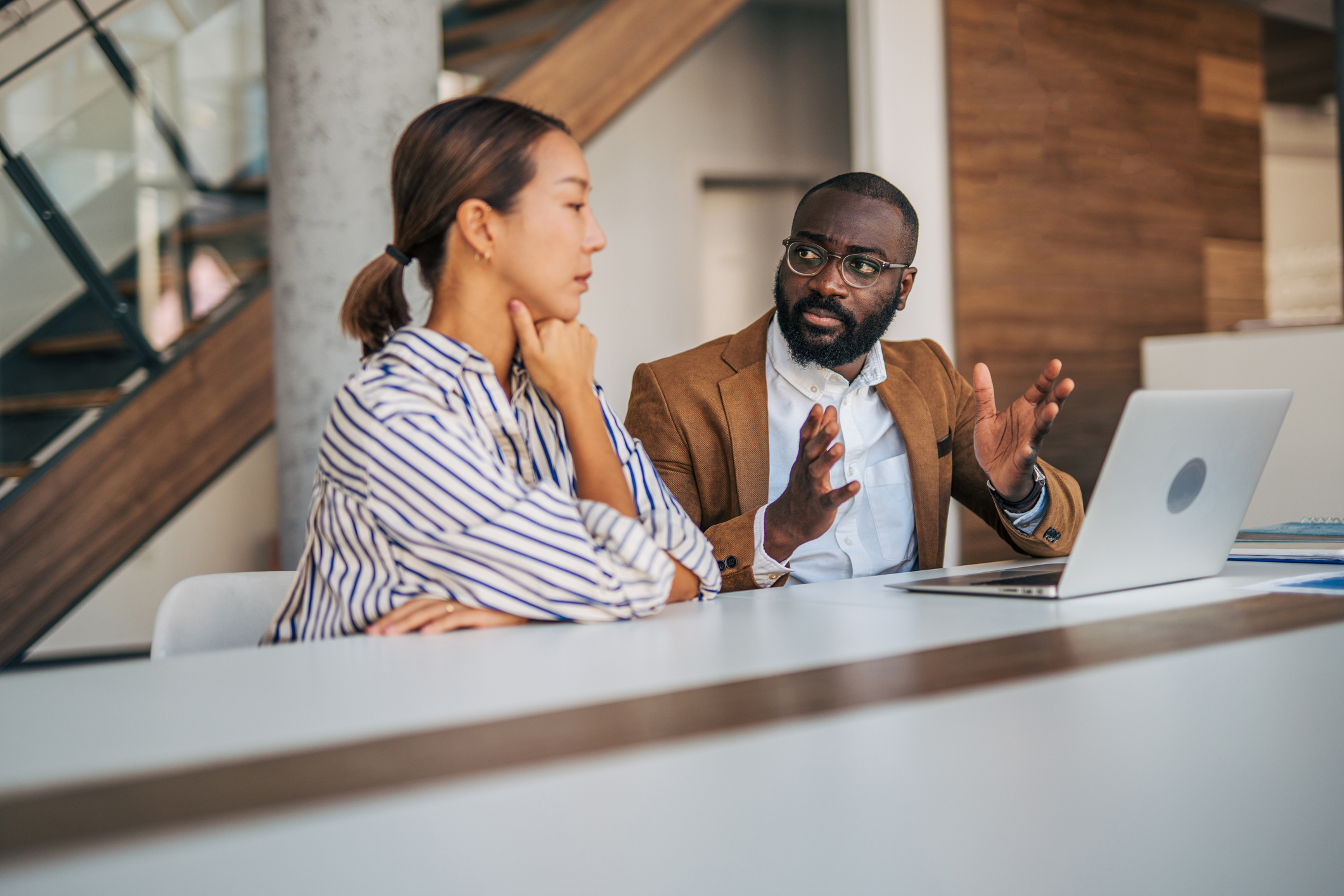 Two people discussing a report on a laptop